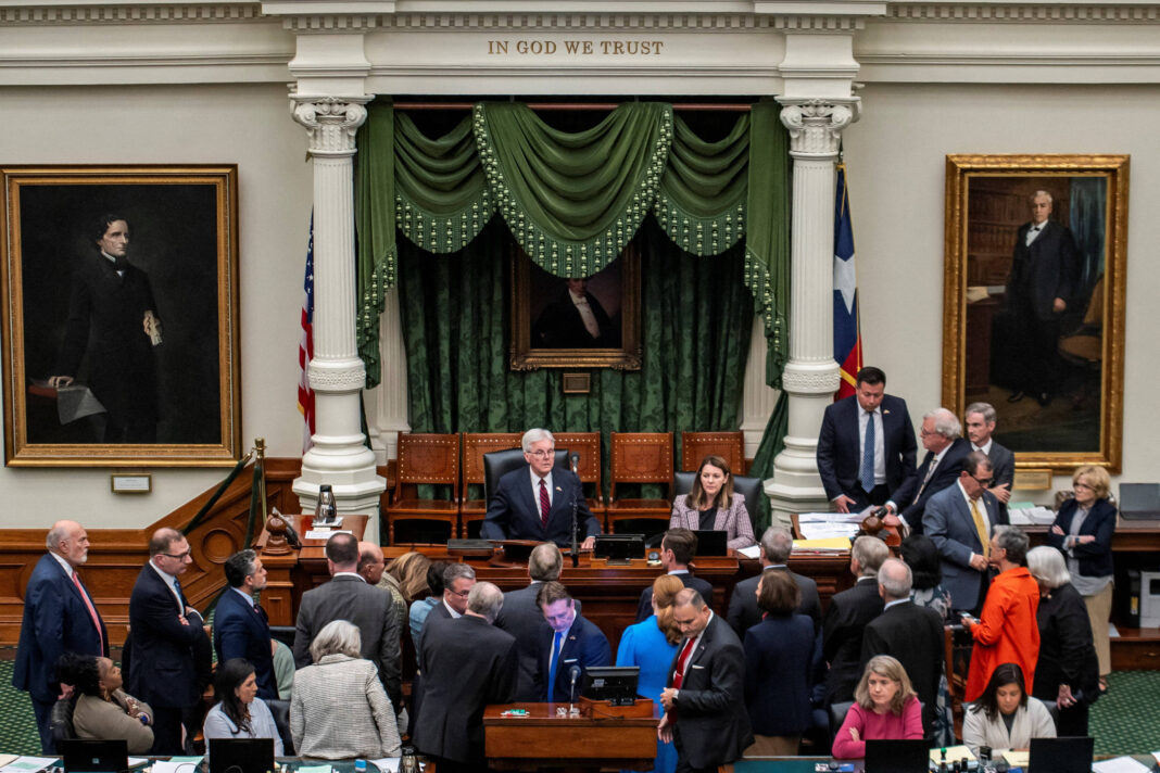 A imagem mostra o interior de uma câmara legislativa, onde várias pessoas estão reunidas em torno de mesas. No centro, há um grupo de legisladores conversando, enquanto outros estão em pé ou sentados. Ao fundo, há cortinas verdes e quadros emoldurados nas paredes, incluindo um retrato de um homem. A frase 