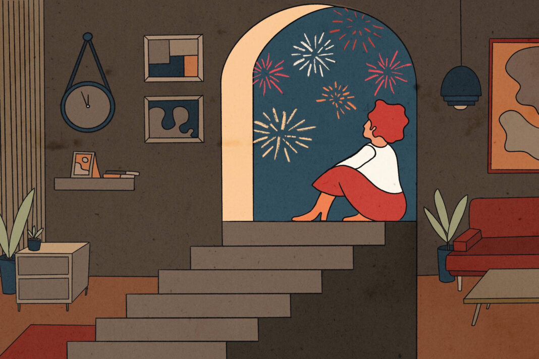 A imagem mostra uma mulher sentada em uma escada, olhando para fora através de uma grande abertura em forma de arco. Ela está vestindo uma blusa branca e uma saia vermelha, com cabelo curto e ruivo. Do lado de fora, há fogos de artifício coloridos iluminando o céu noturno. O ambiente interno é decorado com uma mesa, um sofá vermelho, plantas em vasos e uma parede com quadros. Um relógio de parede também está visível.