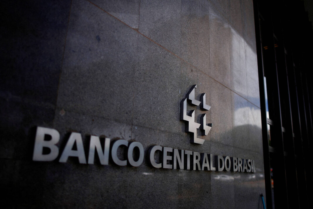 Placa metálica com o nome Banco Central do Brasil fixada em parede de pedra escura, com logotipo ao lado direito.